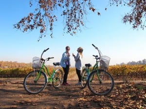 Two ladies with bikes laughing and enjoying themselves in the vineyards of the central valley which is a year round destination