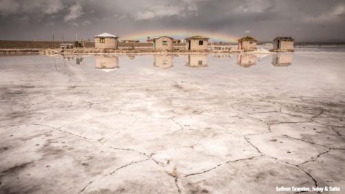 Salinas Grandes, Salta, Argentina. Old wooden huts in background with large white salt plains at the front.