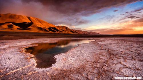Salt Flats near Cafayate/Salta in Argentina. Orange mountains in the sunset with large flat salt plains infront.